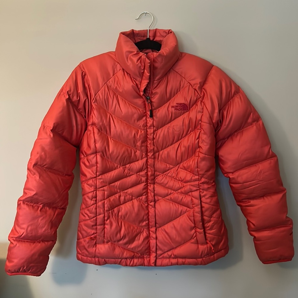A medium sized bright orange North Face puffer coat